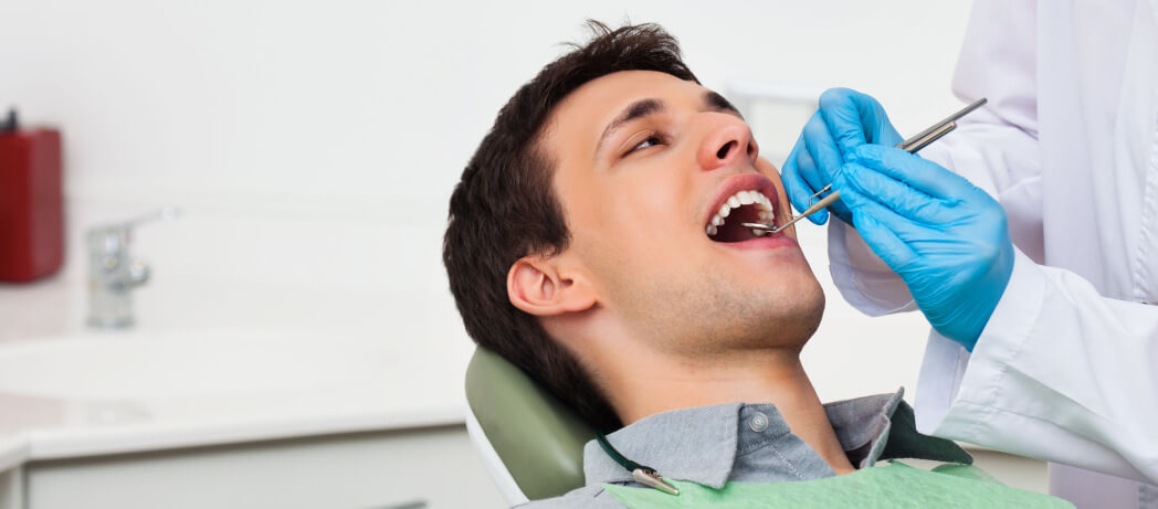 man-in-dental-chair-getting-his-teeth-and-gums-examined